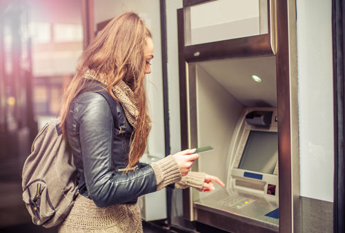 Young woman taking money from ATM